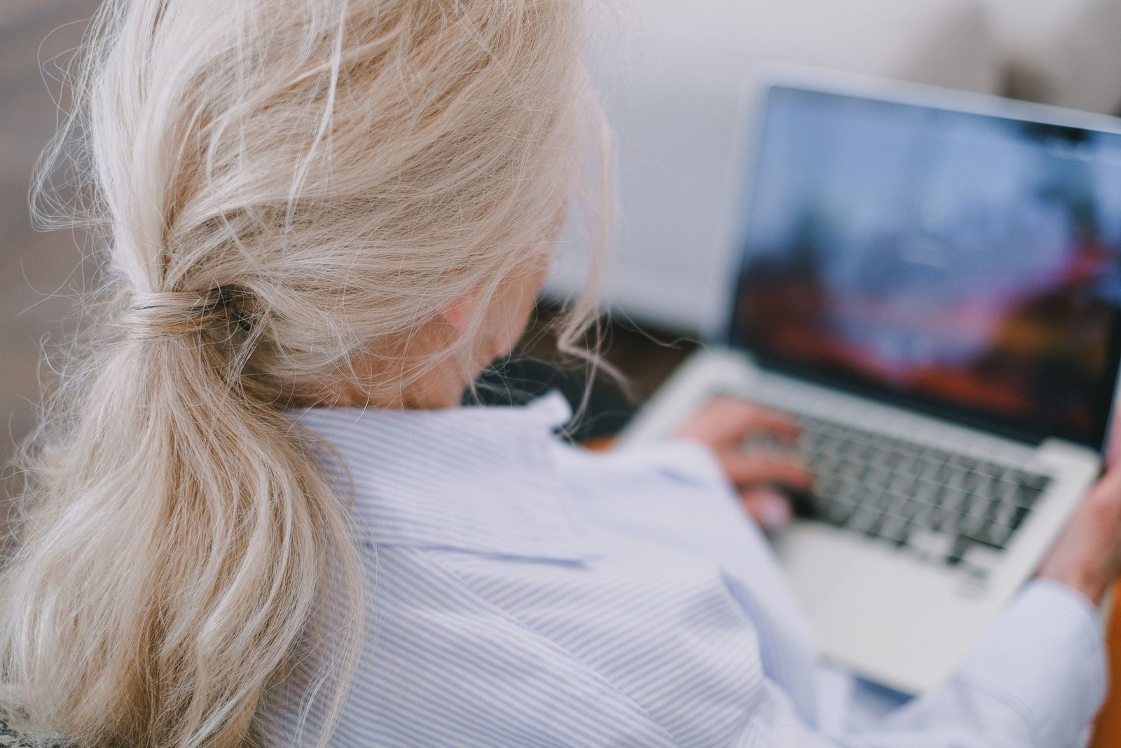 A senior female academic with white hair using a laptop.