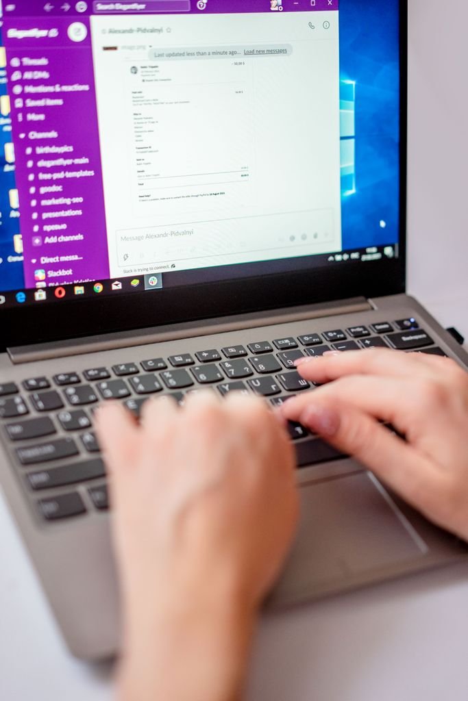 Close-up of hands typing on a laptop keyboard.